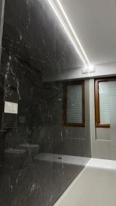 a bathroom with a black marble wall and a window at Grey loft in Torvaianica +17 photos