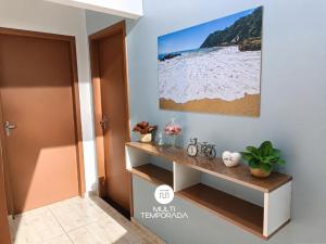 a hallway with a shelf and a painting on the wall at Pousada Família Cordeiro - Penha/SC in Penha