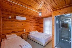 two beds in a room with wooden walls at Adrasan Çıtır Pansiyon in Kumluca