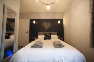 a bedroom with a large white bed with towels on it at Modern Studio - Central Location in Southport +3 photos