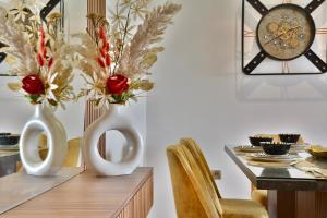 two white vases with flowers on a table with a clock at Marrakech Golf Luxury in Marrakesh