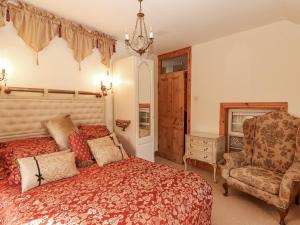 a bedroom with a large bed and a chair at White Heather Cottage in Killaloe