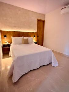 a bedroom with a large white bed in a room at Cumaé Hotel Boutique in Quimbaya