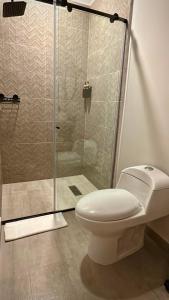 a bathroom with a toilet and a glass shower at Cumaé Hotel Boutique in Quimbaya