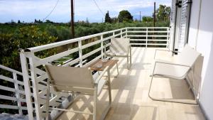 a porch with two chairs and a table and a fence at Στον Λεμονόκηπο in Nerántza