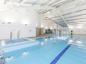 a large swimming pool with blue tiles on the floor at Pine Lodge Spa in Thirsk +17 photos