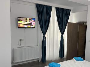 a room with blue curtains and a tv on a wall at The Lighthouse Suite in Mamaia Sat/Năvodari