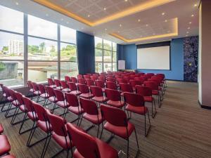 a conference room with red chairs and a white screen at ibis Jacarei in Jacareí