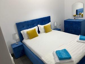 a blue bedroom with a large bed with yellow pillows at The Lighthouse Suite in Mamaia Sat/Năvodari