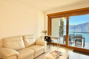 a living room with a couch and a large window at Residence degli Oleandri 4B in Argegno