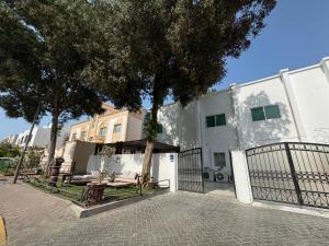 a white building with a tree and a fence at Velmora Cozy 2BR Apartment 20 in Abu Dhabi