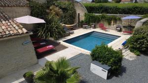 an outdoor swimming pool with chairs and an umbrella at LA MAISON JEROBOAM in Saint-Estèphe