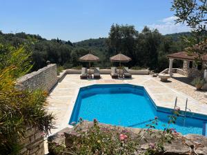 a pool with chairs and umbrellas in a yard at Villa Delphini in Argyrátika
