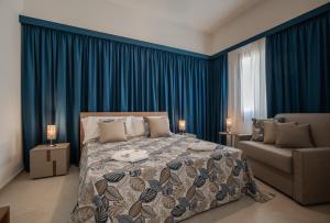 a bedroom with a bed and a couch and blue drapes at Monnalisa Rooms in San Vito lo Capo