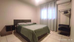 a bedroom with a bed with a green bedspread at Apartamento 11 - 2 Quartos com AC e cama de casal in Toledo