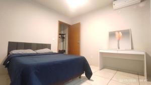 a bedroom with a bed with a blue blanket and a dresser at Apartamento 11 - 2 Quartos com AC e cama de casal in Toledo +3 photos