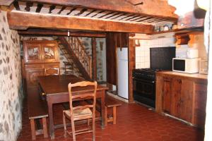 a kitchen with a wooden table and a wooden staircase at Gite d'Aliège in Péone