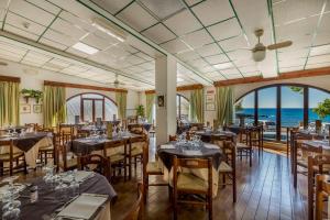 a restaurant with tables and chairs and a view of the ocean at Hotel El Balear in Alghero