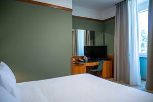 a bedroom with a bed and a desk with a television at Spazio Origine - Studio Hotel in Monopoli