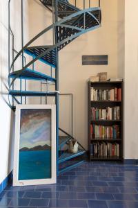 a painting on a floor next to a book shelf at Greco Hotel in Hydra