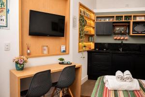 ein Zimmer mit einem Schreibtisch, zwei Stühlen und einem Fernseher in der Unterkunft Loft Veneto in Maringá