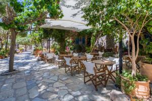 an outdoor patio with tables and chairs under trees at Greco Hotel in Hydra