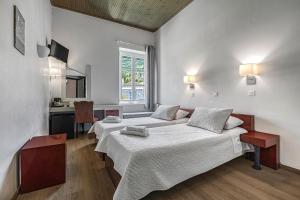 a bedroom with two beds and a desk in it at Greco Hotel in Hydra