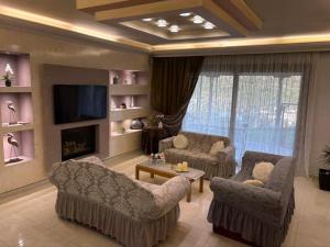 a living room with couches and a tv and a fireplace at Casa Maria Tsampika-Spacious Home with 2 Bathrooms & Free Parking in Psinthos