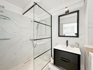 a white bathroom with a shower and a sink at Duplex La Plage Orient Bay in Orient Bay +14 photos
