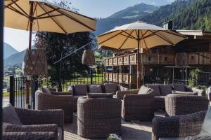 Eine Gruppe von Stühlen und Sonnenschirmen auf einer Terrasse in der Unterkunft Genusshotel Vermala Montafon in Sankt Gallenkirch + 141 Fotos