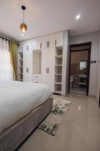 a bedroom with a large white bed and a living room at Smart Luxury Apartment, Bunga in Kampala