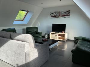 a living room with a couch and a tv at LE BRIDGE in Bénouville