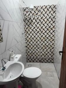 a white bathroom with a toilet and a sink at Hotel Colinas in Cajuapara