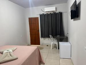 a bedroom with a bed and a television and a table at Hotel Colinas in Cajuapara