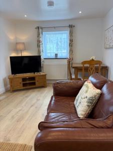 a living room with a brown leather couch and a television at Pendragon Studio in Penzance