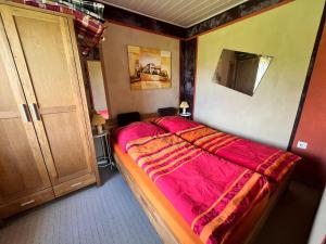 a bedroom with a bed with a red comforter at Gemütlicher Bungalow in Pepelow nahe dem Meer in Pepelow