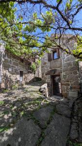 a stone building with a door and a tree at Casa D'Zelo - Gerês in Montalegre