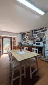 a table and chairs in a kitchen with a stone wall at Casa D'Zelo - Gerês in Montalegre +21 photos