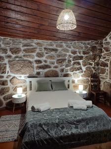 a bedroom with a stone wall with a bed at Casa D'Zelo - Gerês in Montalegre