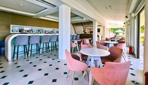 a restaurant with pink chairs and tables and a bar at Sandy Bay Hotel in Plomari