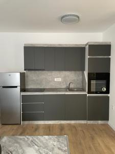 a kitchen with gray cabinets and a sink and a refrigerator at Adora's Apartment in Peje