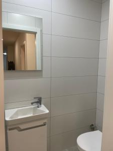 a white bathroom with a sink and a mirror at Adora's Apartment in Peje +12 photos