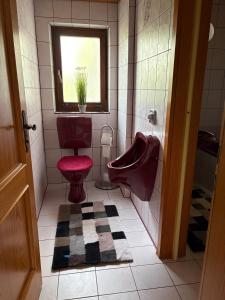 a bathroom with a red toilet and a window at Ferienwohnung Maxi in Pottenstein +12 photos
