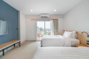 a hotel room with two beds and a television at Manditel North Pattaya in North Pattaya