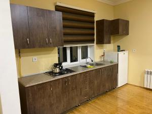 eine Küche mit Holzschränken und einem weißen Kühlschrank in der Unterkunft Alp Hotel in Qax