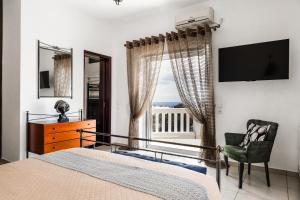 a bedroom with a bed and a chair and a window at Selenophile Villa with heated pool in Monolithos