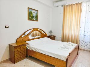 a bedroom with a bed with a wooden headboard at Shtepi Manuel in Sarandë