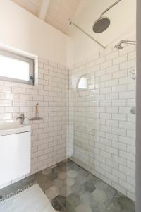 a white tiled bathroom with a shower and a sink at 1HA Tagyon Vendégház in Tagyon