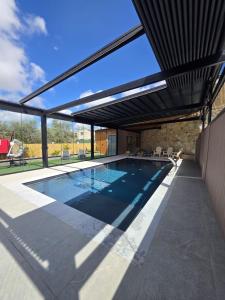 a swimming pool in a house with a glass extension at Rosa Carmel in Dāliyat el Karmil
