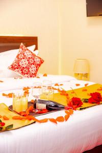 a tray with drinks and flowers on a bed at Lemon hills hotel in Runda